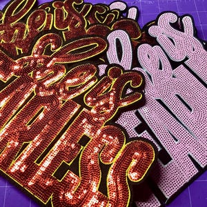 Może przedstawiać: Biały ceramiczny kubek z czarnym uchem i napisem "But First, Coffee" w czarnym kolorze. Kubek jest umieszczony na rozmytym tle, sugerującym przytulne otoczenie.