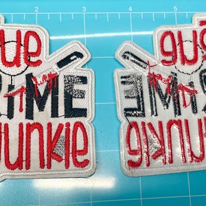 Op de afbeelding: Twee geborduurde patches met de tekst "TRUE CRIME JUNKIE" in rood en zwart. De patches hebben een handafdruk, een mes en een doelwit. De patches zijn wit met een rode rand.
