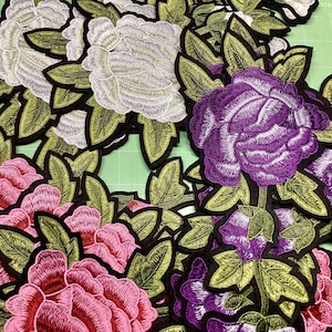 Puede incluir: Parches florales bordados en varios colores, incluyendo rosa, morado y blanco. Cada parche presenta costuras detalladas, hojas verdes y un borde negro. Adecuados para manualidades textiles y adornos.