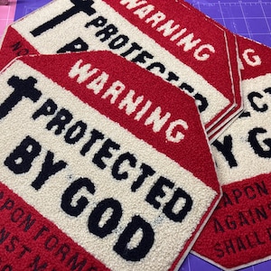 Puede incluir: Alfombras decorativas hexagonales rojas, blancas y negras con el texto "WARNING PROTECTED BY GOD" y "NO WEAPON FORMED AGAINST ME SHALL PROSPER". Las alfombras tienen una apariencia texturizada y afelpada.