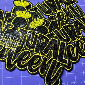 May include: A collection of black and yellow sequined patches featuring the text 'NATURAL QUEEN' in a bold, stylized font. Each patch includes a graphic icon of a silhouette head with an afro pick comb and a crown, all rendered in sequins.