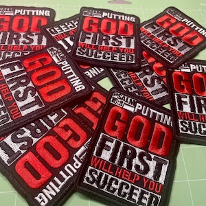 May include: A collection of black embroidered patches with red and white text. The patches read "PUTTING GOD FIRST WILL HELP YOU SUCCEED". The patches are square and have a black border.