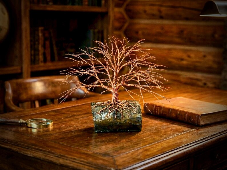Puede incluir: Una escultura decorativa de &aacute;rbol hecha de alambre de cobre fino y retorcido. El &aacute;rbol presenta una copa ancha y extendida de finas ramas de alambre y est&aacute; anclado a una base rectangular texturizada que parece un trozo de madera oscura y musgosa.
