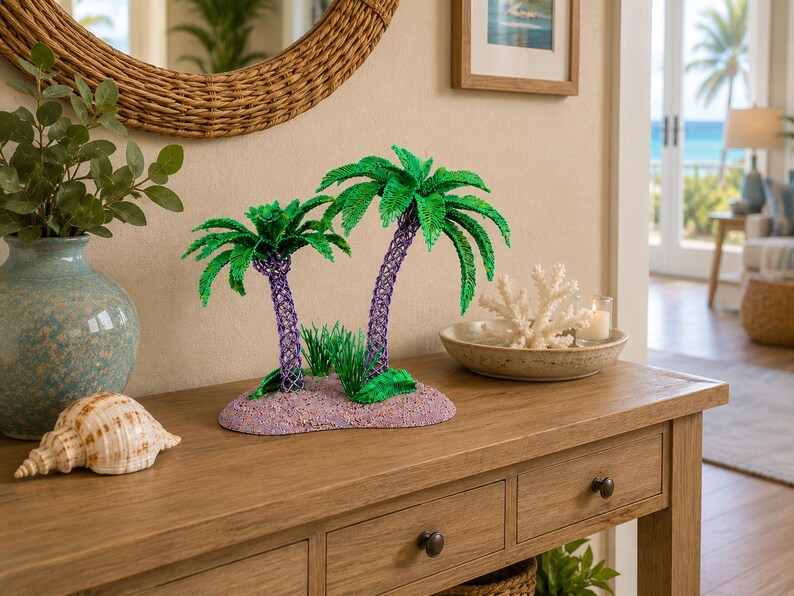 May include: A decorative sculpture featuring two palm trees with green fronds and purple textured trunks, set on a sandy-colored base with small green grass accents. The sculpture is crafted with a detailed, woven-like texture on the trunks.