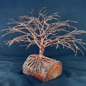 Puede incluir: Una escultura decorativa de &aacute;rbol hecha de alambre de cobre trenzado. El &aacute;rbol presenta una red compleja de ramas delgadas y un tronco grueso y trenzado. La base es un tronco de madera cil&iacute;ndrico con corteza y veta visibles.