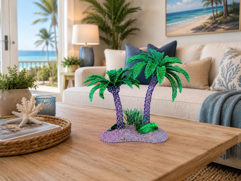 May include: A decorative sculpture featuring two palm trees with vibrant green fronds and textured purple trunks, set upon a small, rounded, light purple base that mimics a sandy island, accented with small green foliage at the base of the trees.