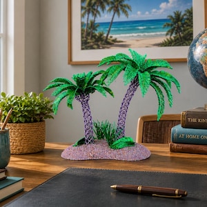 May include: A decorative sculpture featuring two palm trees with vibrant green fronds and textured purple trunks, set upon a small, rounded, light purple base. The sculpture includes small green grass-like accents at the base of the two palm trees.