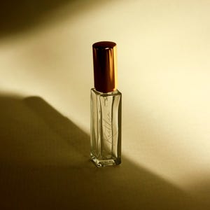 May include: A clear, rectangular glass perfume bottle with a metallic gold cylindrical cap. The front of the bottle features the name Kaitlin written in a delicate, cursive script. The bottle is empty and stands upright with sharp, defined edges.