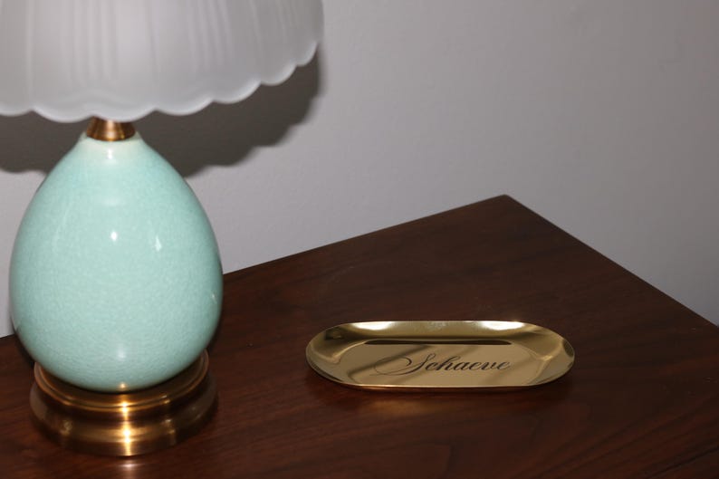 Lifestyle shot of gold trinket tray on white cloth with jewelry and accessories, minimalist modern look.
