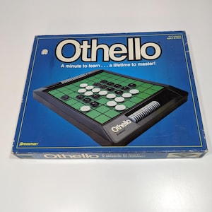 May include: Othello board game in a blue box. The game board is black and green with white and black game pieces. The box has the game title "Othello" and the tagline "A minute to learn... a lifetime to master!"