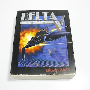 May include: A vintage video game box for "Delta V" featuring a futuristic spaceship design against a backdrop of a fiery sky and a cityscape. The box has the text "DELTA V" and "Bethesda Softworks".