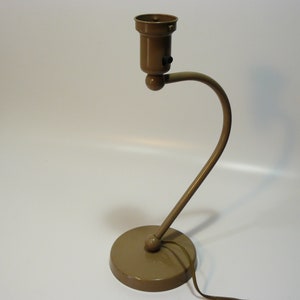 May include: A brown metal desk lamp with a flexible arm and a round base. The lamp has a simple design and a classic look.