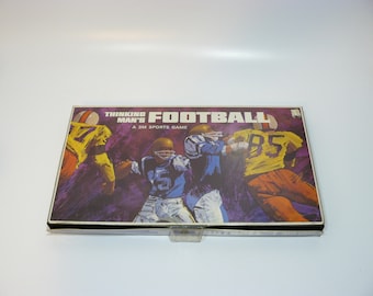 May include: A vintage board game box with a purple background and a colorful illustration of football players. The box reads "Thinking Man's Football, A 3M Sports Game".
