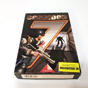 May include: A vintage "Corridor 7" video game box. The box art features a futuristic soldier aiming a weapon, with a menacing creature in the background. The game's title is prominently displayed in a bold, orange font.