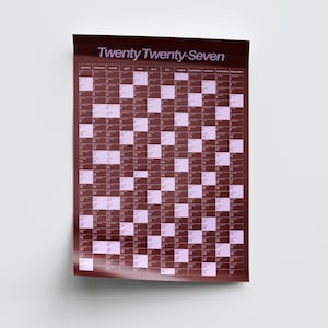 May include: A wall calendar for the year 2027 with the text Twenty Twenty-Seven at the top. The design features a grid layout with dark maroon and light lavender alternating rectangular blocks representing days of the year.