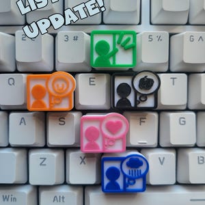May include: A white keyboard with custom keycaps featuring small illustrations. The keycaps are in various colours and depict people and symbols, including a heart, magnifying glass, and rain cloud. The text "LISTING UPDATE!" is visible.