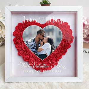 Può includere: Cornice bianca con un cuore di rose rosse. All'interno, una foto di una coppia che si bacia. Il testo "James & Mary" e "Fuck Valentine's Day, I Love You Every Day" sono visibili.