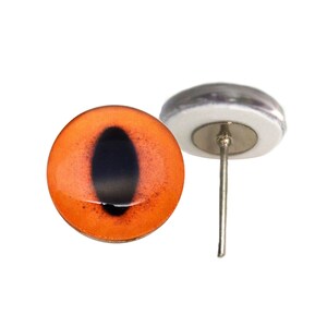May include: Orange glass eye with a black pupil, mounted on a silver pin for use in crafts and taxidermy.