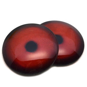 May include: Two red and black round glass eyes with a black pupil in the center. The eyes are shiny and have a gradient effect from dark red to light red.