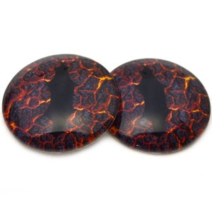Puede incluir: Dos ojos redondos de plástico negro con un diseño de flujo de lava. Los ojos tienen un esquema de color rojo, naranja y negro.