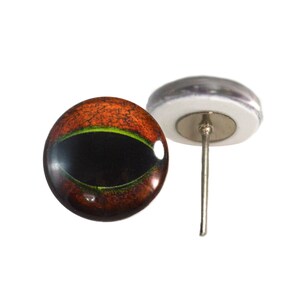 Op de afbeelding: Een paar realistische glazen ogen met een bruine en oranje iris en een groene ring rond de zwarte pupil. De ogen zijn gemonteerd op een metalen pin om te bevestigen aan een knuffeldier of knutselproject.