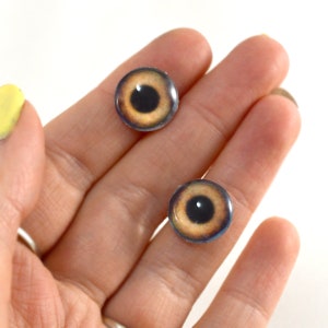 Puede incluir: Dos ojos de mu&ntilde;eca de pl&aacute;stico marr&oacute;n y negro con un iris y una pupila realistas.
