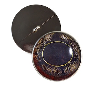 May include: A round, black button with a silver loop on the back. The front of the button has a colorful, detailed image of an eye.