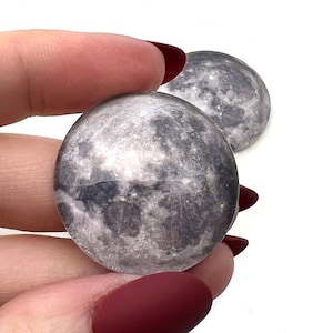 Pode incluir: Dois pisa-papéis redondos de vidro com uma imagem detalhada da superfície da lua.