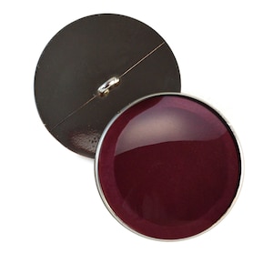 May include: Two-piece button set. The front button is a glossy, deep burgundy color with a silver-colored rim. The back button is a dark, metallic brown with a silver-colored shank for sewing. The buttons are round.