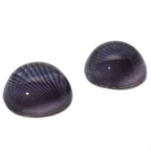 May include: Two purple glass dome-shaped cabochons with a striated pattern.