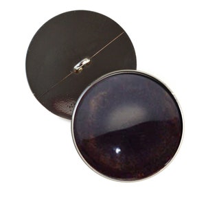 May include: A black button with a silver metal rim and a silver loop on the back. The front of the button has a dark purple, galaxy-like design.