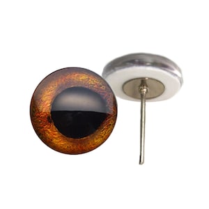 May include: A pair of brown and black glass eyes with a metallic sheen. The eyes are on a white backing with a metal pin.