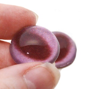 May include: Two round, iridescent purple glass eyes with a dark red centre. The eyes are slightly convex and have a shiny finish.