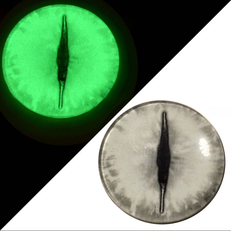 May include: A pair of glow-in-the-dark eyes with a black vertical slit pupil. The eyes are white with a green glow. The eyes are round and have a textured surface.