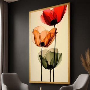 Op de afbeelding: Een rechthoekig wandkunstwerk in een gouden lijst met een verticale opstelling van drie doorschijnende bloemen. De bovenste bloem is rood, de middelste oranje en de onderste groen. Elke bloem heeft dunne zwarte stelen tegen een crèmekleurige achtergrond.