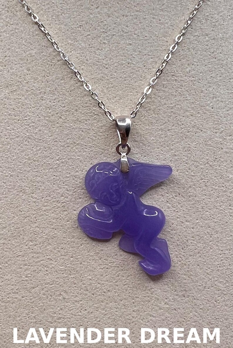Puede incluir: Collar con colgante lavanda con dise&ntilde;o de &aacute;ngel. El colgante cuelga de una fina cadena plateada. El texto "LAVENDER DREAM" se muestra en la parte inferior de la imagen.