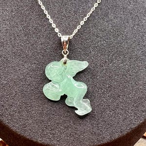 Puede incluir: Un collar de cadena plateada con un colgante que representa un &aacute;ngel tallado en verde claro. El colgante tiene forma de querub&iacute;n con alas. El texto "SAGE SERENITY" est&aacute; en la parte inferior de la imagen.