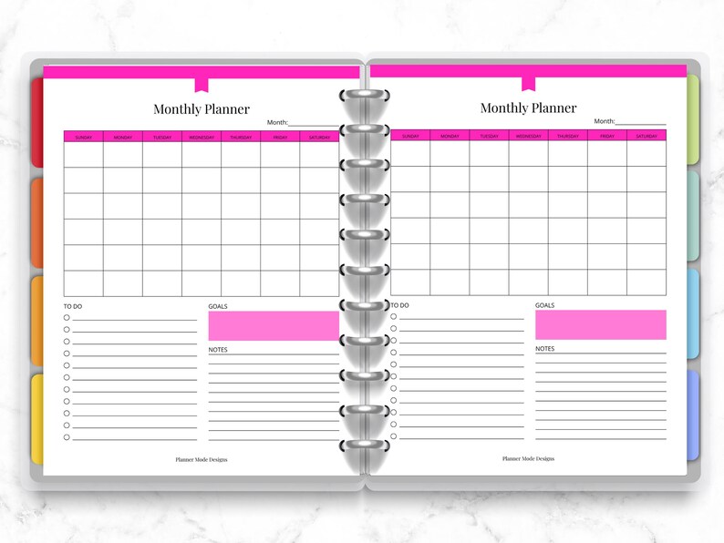 May include: Open planner with a pink and white monthly planner spread. The left page has a section for "To Do" and "Goals", while the right page mirrors this layout. The planner is bound with silver rings and has colorful page dividers.