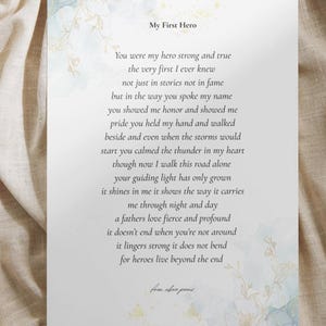 May include: A printed card featuring the text "My First Hero" and a poem about a father's love. The card has a watercolour floral design in blue and gold. The background is a beige fabric.