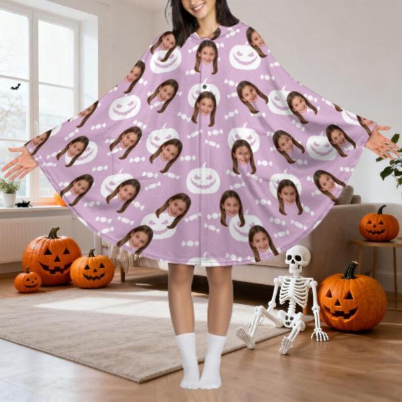 May include: A light purple Halloween poncho featuring a repeating pattern of smiling jack-o'-lanterns, candy, and a young girl's face. The poncho is worn by a person standing in a room with carved pumpkins and a skeleton.