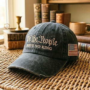 以下が含まれることがあります： 金色の文字で「We the People SERVE NO KING」と刺繍された、色あせたネイビーブルーの野球帽。 アメリカ国旗のパッチが側面にあります。 キャップはカーブしたつばと使い古された外観をしています。