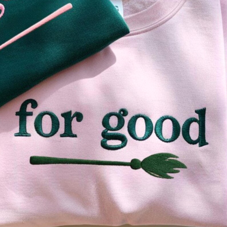 K&ouml;nnte beinhalten: Ein hellrosa Sweatshirt mit dem gestickten Schriftzug "for good" in Dunkelgr&uuml;n. Eine gr&uuml;ne Besen-Grafik befindet sich unter dem Text. Dunkelgr&uuml;ner Stoff ist in der oberen linken Ecke sichtbar.