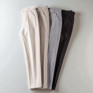 May include: Four pairs of tailored pants in varying neutral colors: off-white, tan, gray, and black. Each pair features a classic design with a waistband, pockets, and a straight leg. The pants are neatly arranged, showcasing their different hues and textures.