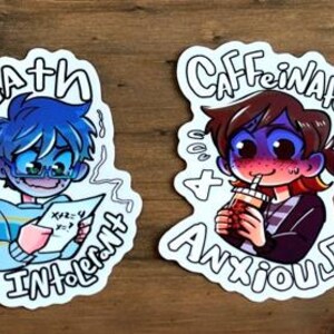 May include: Two white stickers with cartoon illustrations. One shows a blue-haired character with glasses holding a math problem, the text reads "Math Intolerant." The other depicts a person drinking a beverage, with the text "Caffeinated + Anxious."