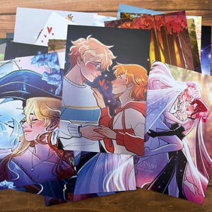 May include: A collection of rectangular art prints featuring colorful anime-style illustrations of couples in various romantic poses. The prints display diverse characters with vibrant hair colors, detailed clothing, and expressive faces, layered together in a stack.