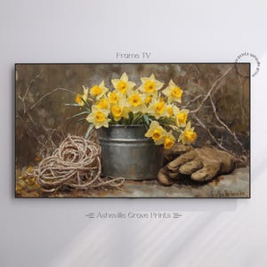 May include: A framed painting depicts a still life with yellow daffodils in a metal bucket, a coil of rope, and a pair of work gloves. The artwork has a rustic, vintage aesthetic, with the text "Frame TV" at the top.