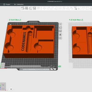 May include: Two orange 3D-printed boxes, labeled "2 inch Box" and "1.5 inch Box", with internal compartments. The larger box has the word "CODENAMES" printed on it. The boxes are displayed on a computer screen with a software interface.
