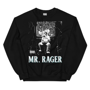 以下が含まれることがあります： 黒いスウェットシャツ。白と黒の漫画のヘラジカのキャラクターが星空の背景の前に座っているグラフィック。テキスト「MR. RAGER」は白とティールで印刷されています。「Seattle Mariners 5000 Mojo」の文字は白で印刷されています。