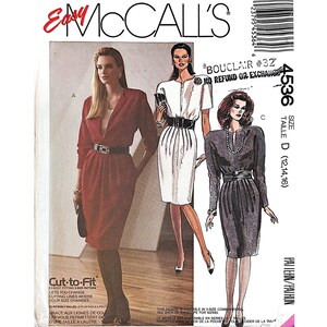 May include: Vintage McCall's sewing pattern with illustrations of three dresses. The pattern includes a red dress with a belt, a white dress with a zipper, and a grey dress with a belt. The pattern size is D (12,14,16). The text "Easy McCall's" is visible.