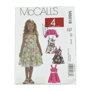May include: McCall's M6018 sewing pattern envelope for children's dresses in sizes 3-5. The front features a child wearing a sleeveless dress with a multi-colored polka dot pattern, alongside illustrations of four dress variations and a bolero.